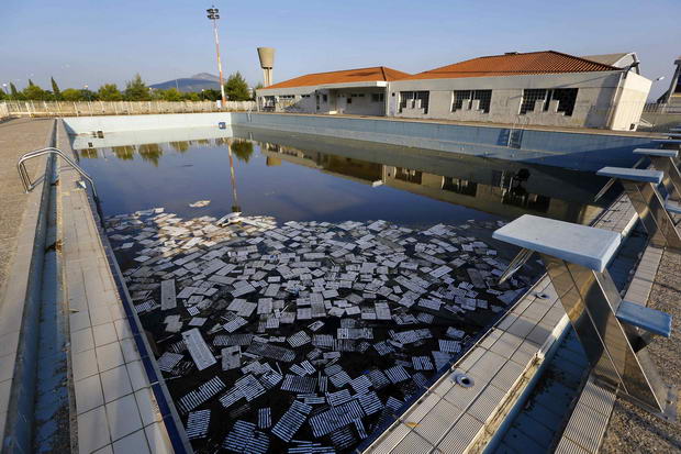 Image: Garbage floats in a deserted swimming pool at the Olympic Village in Thrakomakedones
