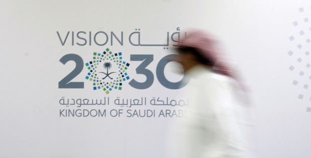 A man walks past the logo of Vision 2030 after a news conference, in Jeddah